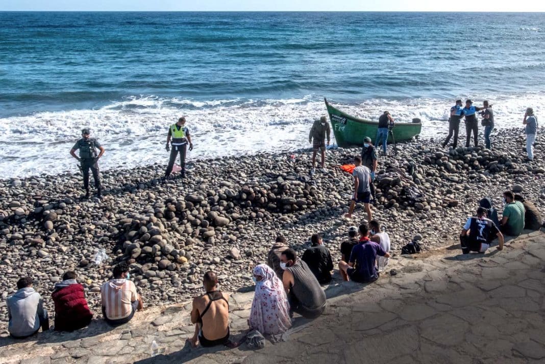 Migranti sorvegliati dalla polizia spagnola dopo essere sbarcati sulla costa delle Isole Canarie